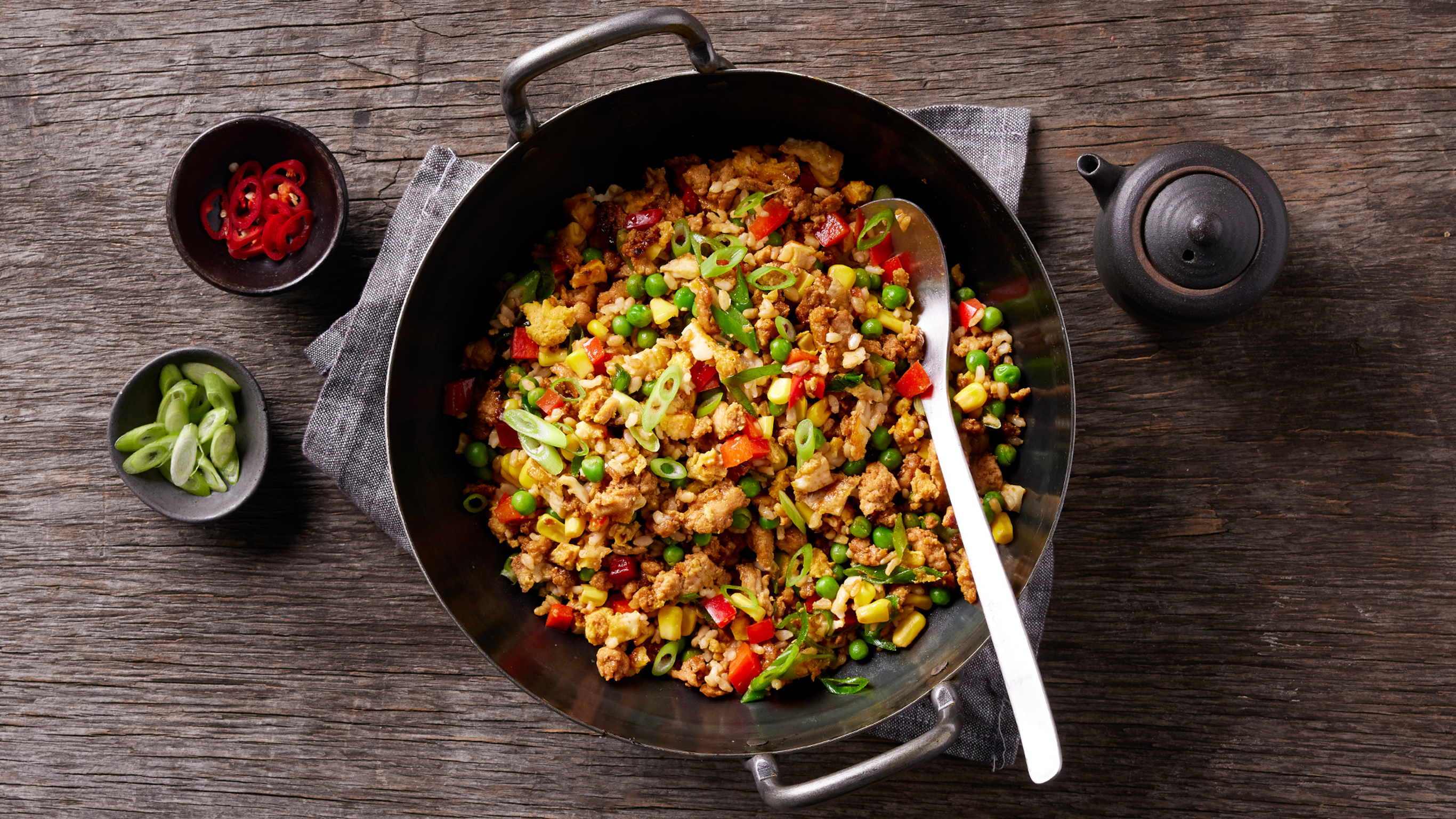 A wok of Centr's Cheat's Chicken Fried Rice sits on a grey napkin, ready for serving.