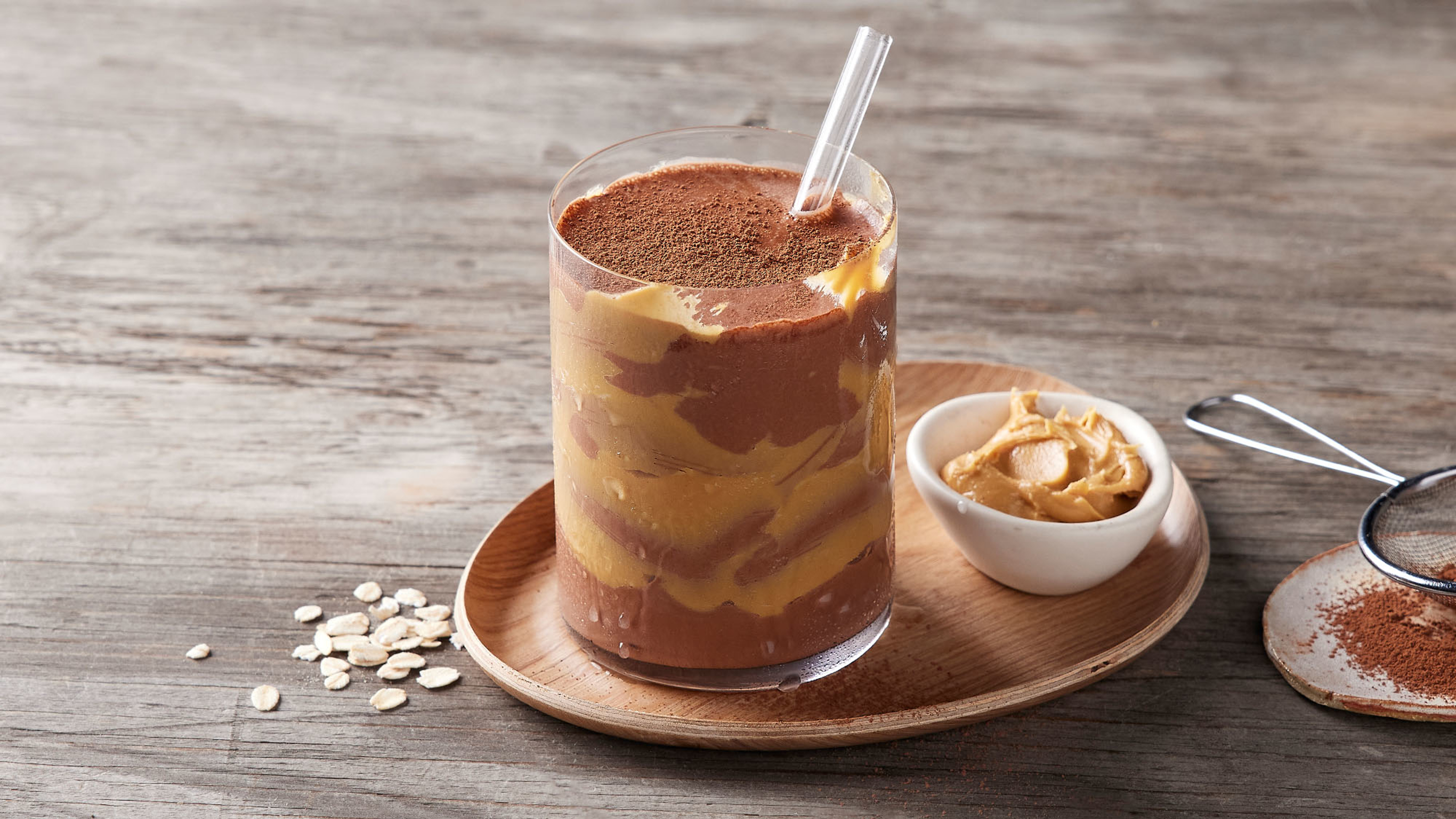 A glass of Centr's Choc Peanut Butter Super Smoothie is ready for drinking.