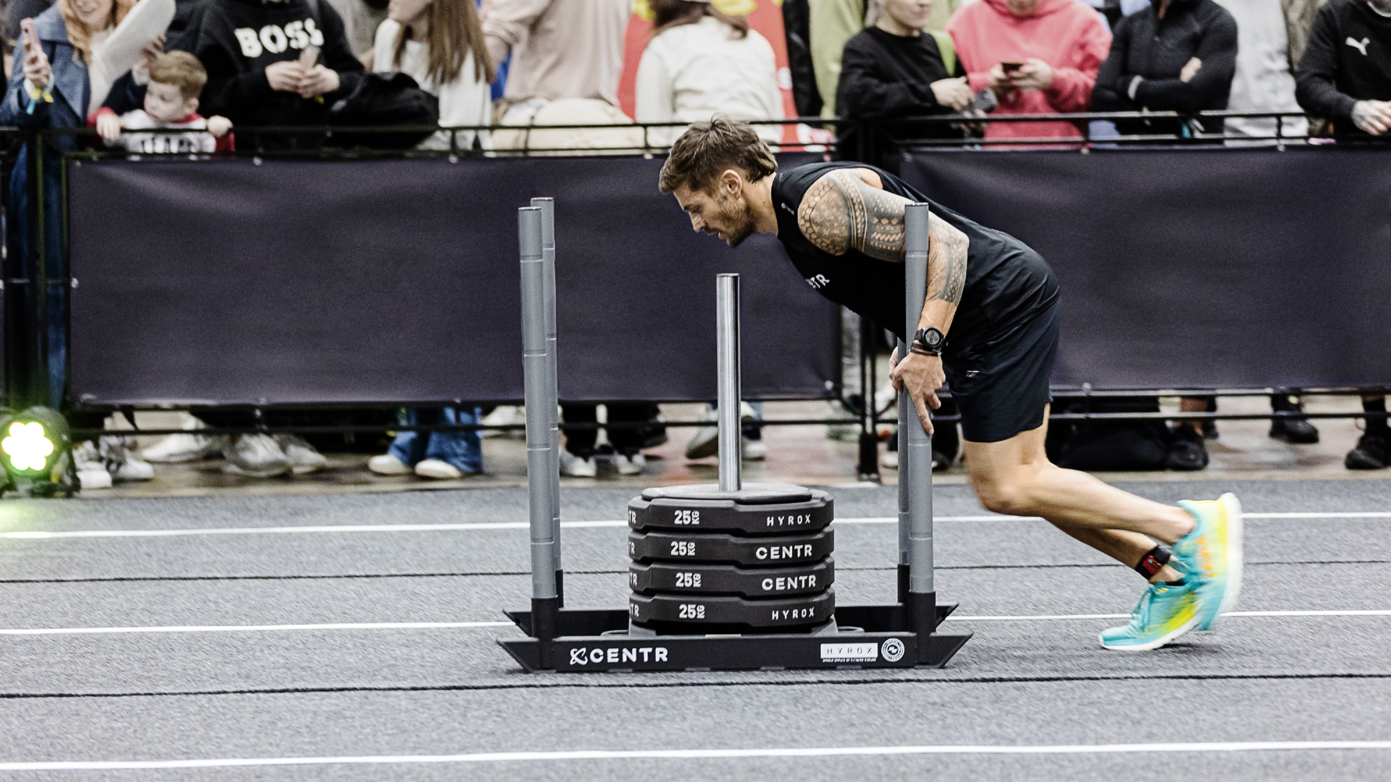 Luke Zocchi pushes a weighted sled during a HYROX race.