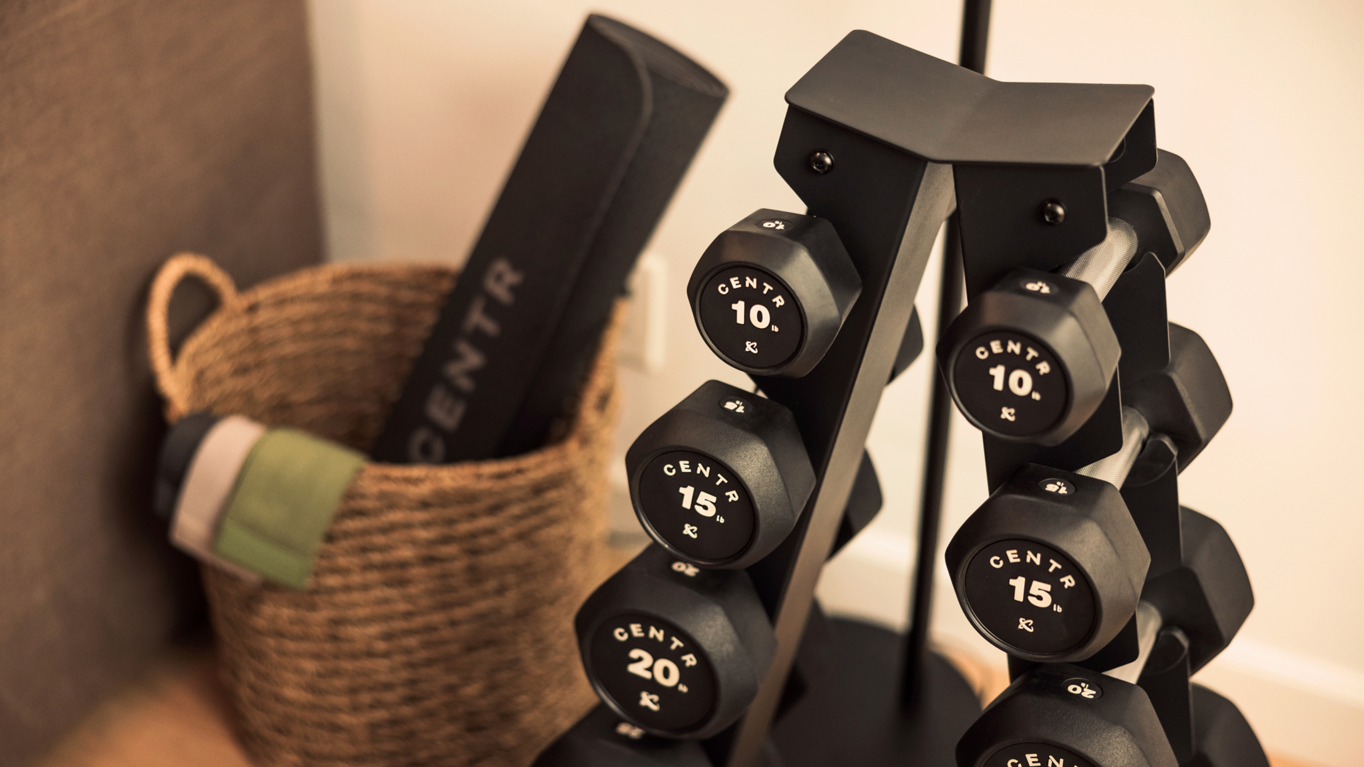 An A-frame of Centr's hex dumbbells sits in the corner of a lounge room.