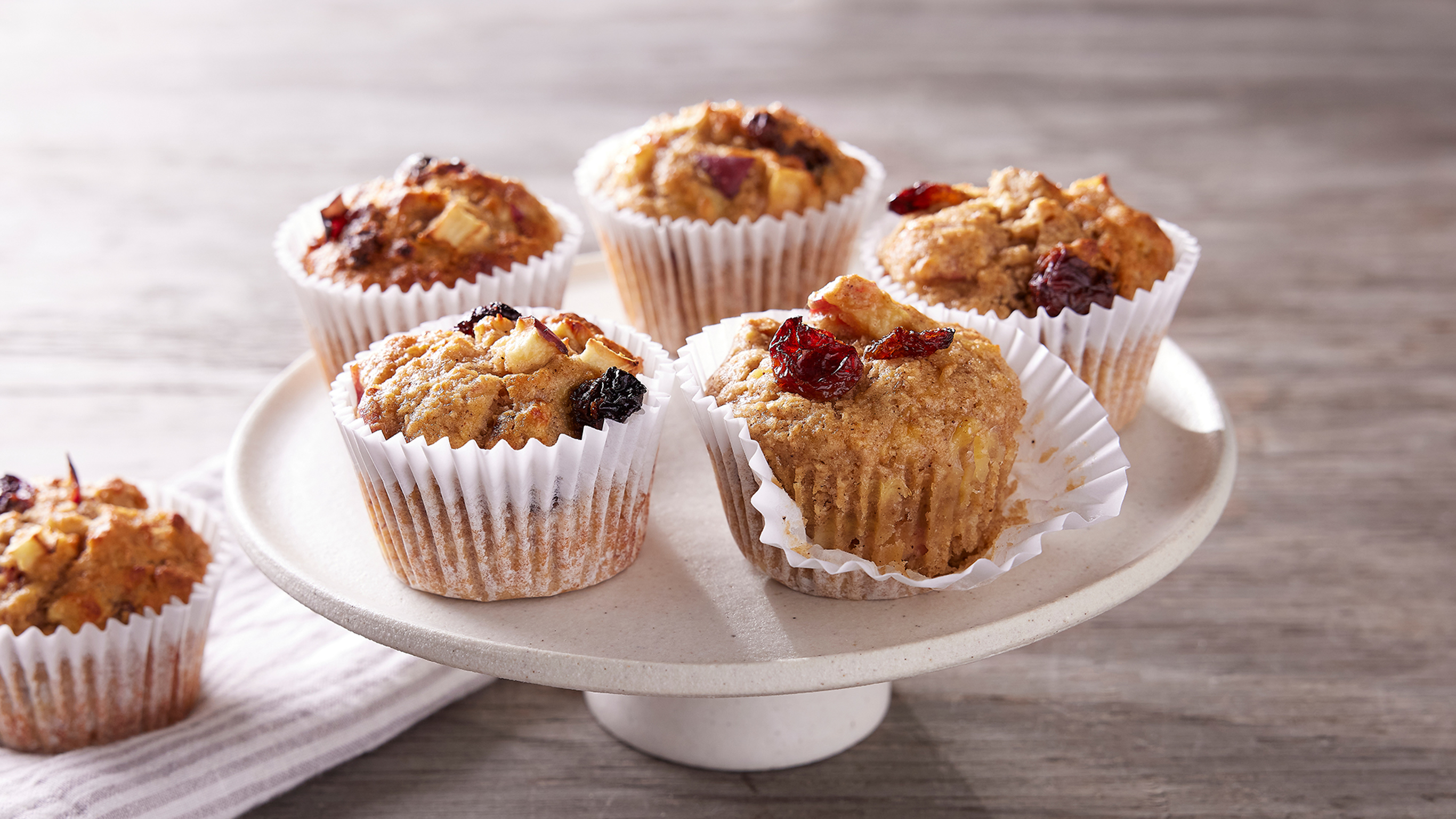 Apple raisin muffins from the Centr menu sit on a white ceramic cake stand, ready for eating.