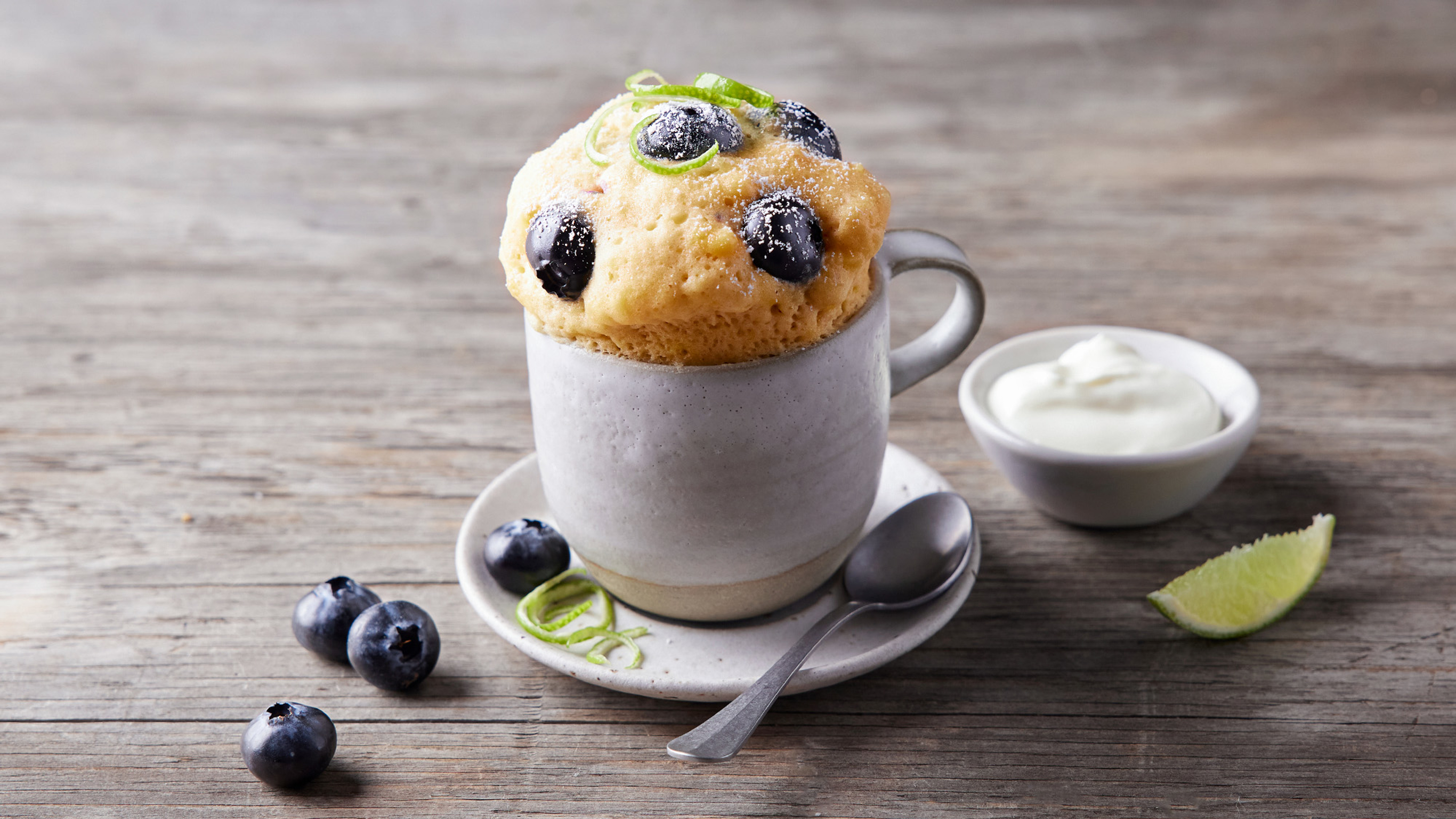 A mug of Centr's Blueberry and lime mug muffin is ready for eating.