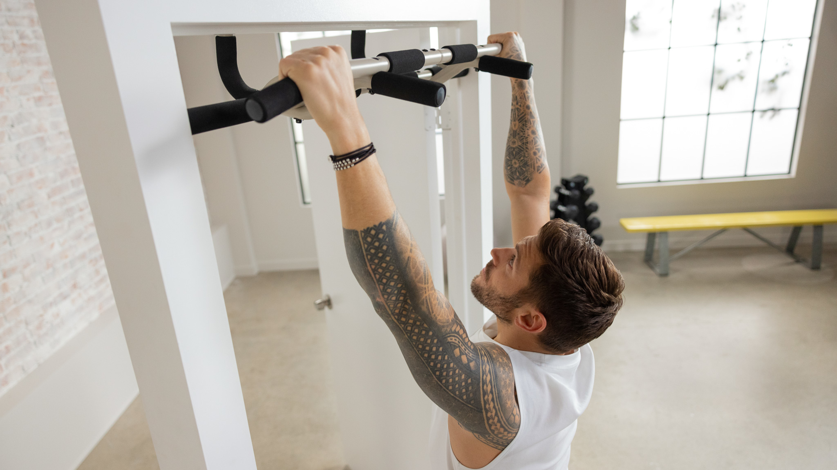 Luke Zocchi hangs from the Centr pull-up bar set up in a free-standing frame .