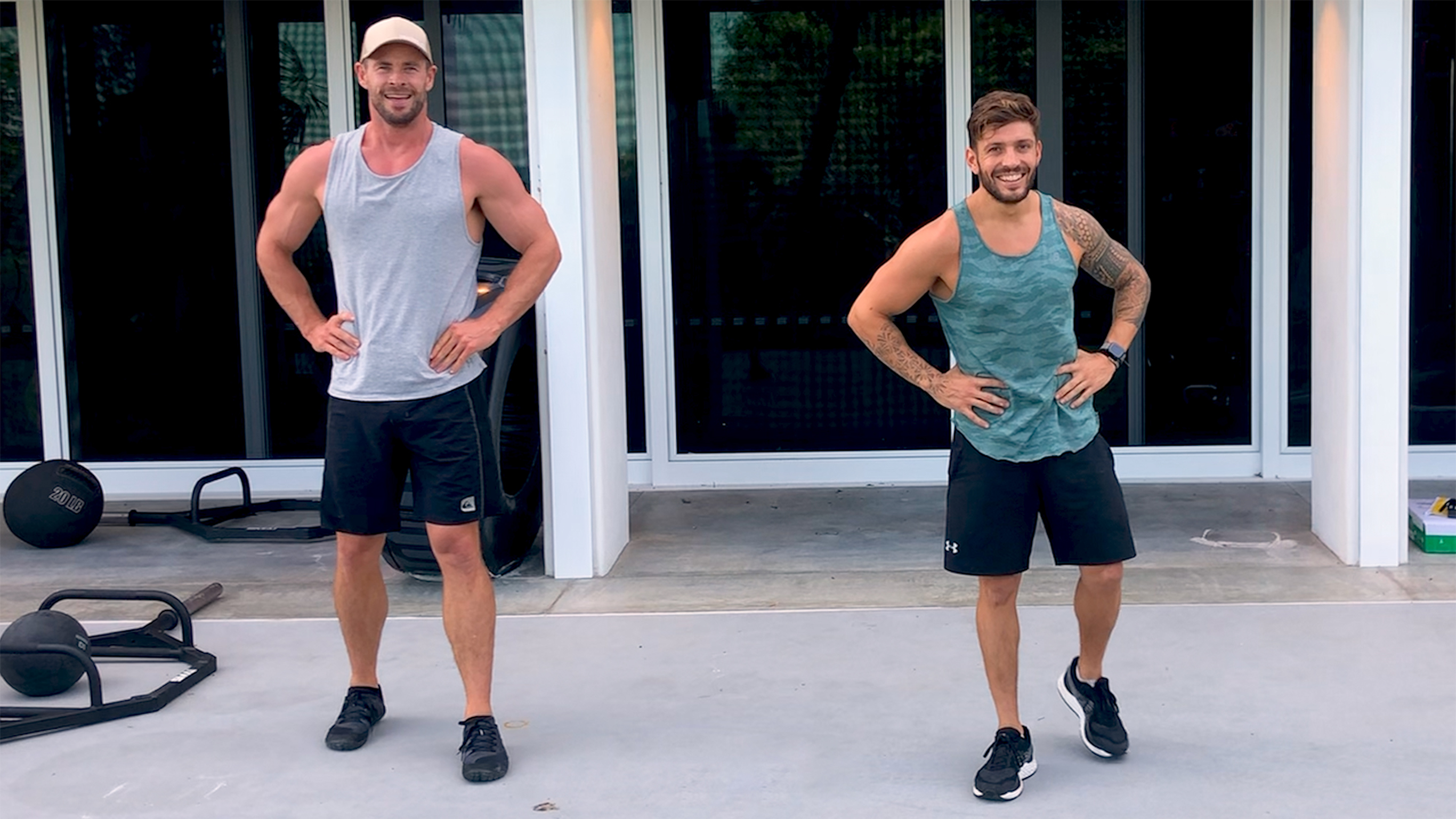 Chris Hemsworth and Luke Zocchi make a joke while working out on an outdoor patio.
