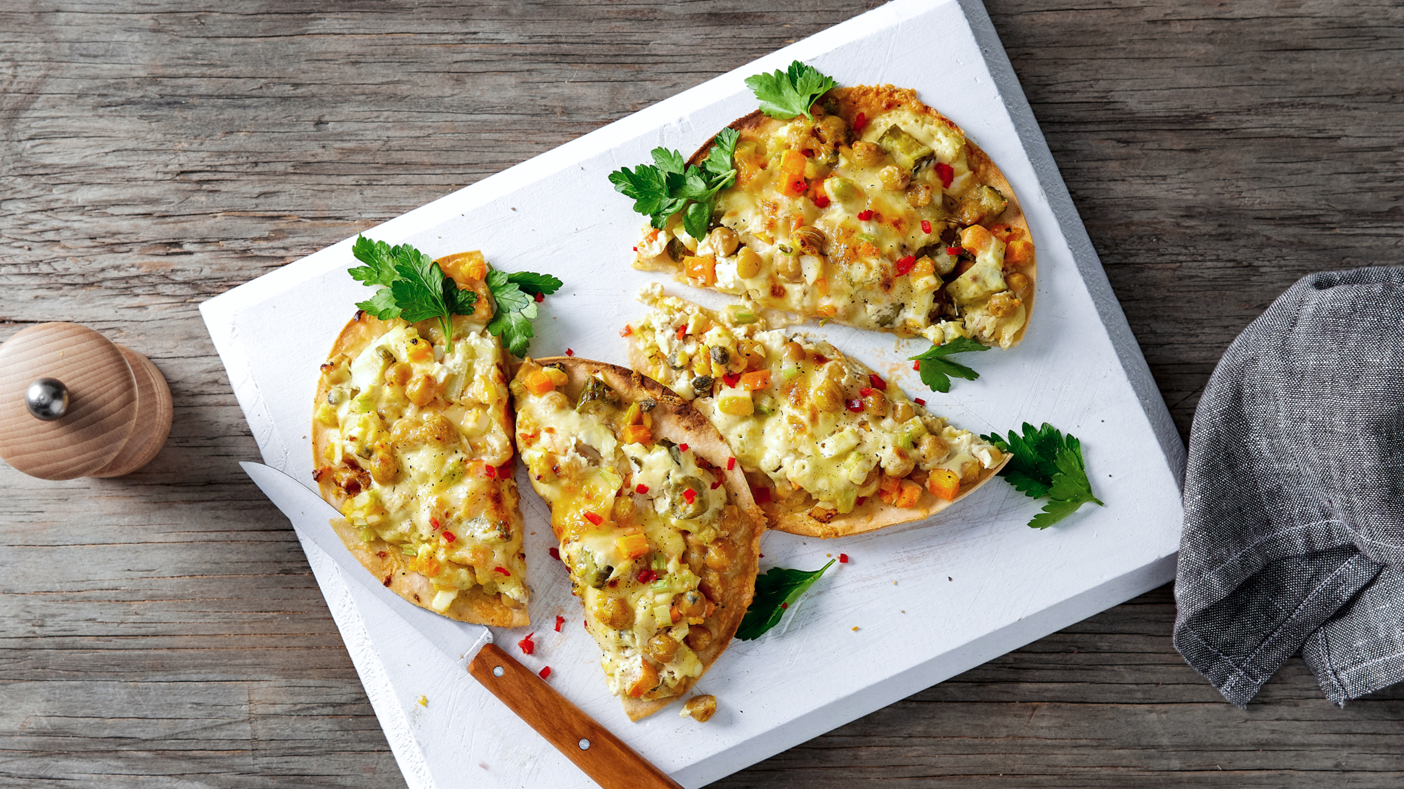 Rounds of Centr's Chickpea “Tuna” Melt, cut in half, rest on a white cutting board, ready for eating.
