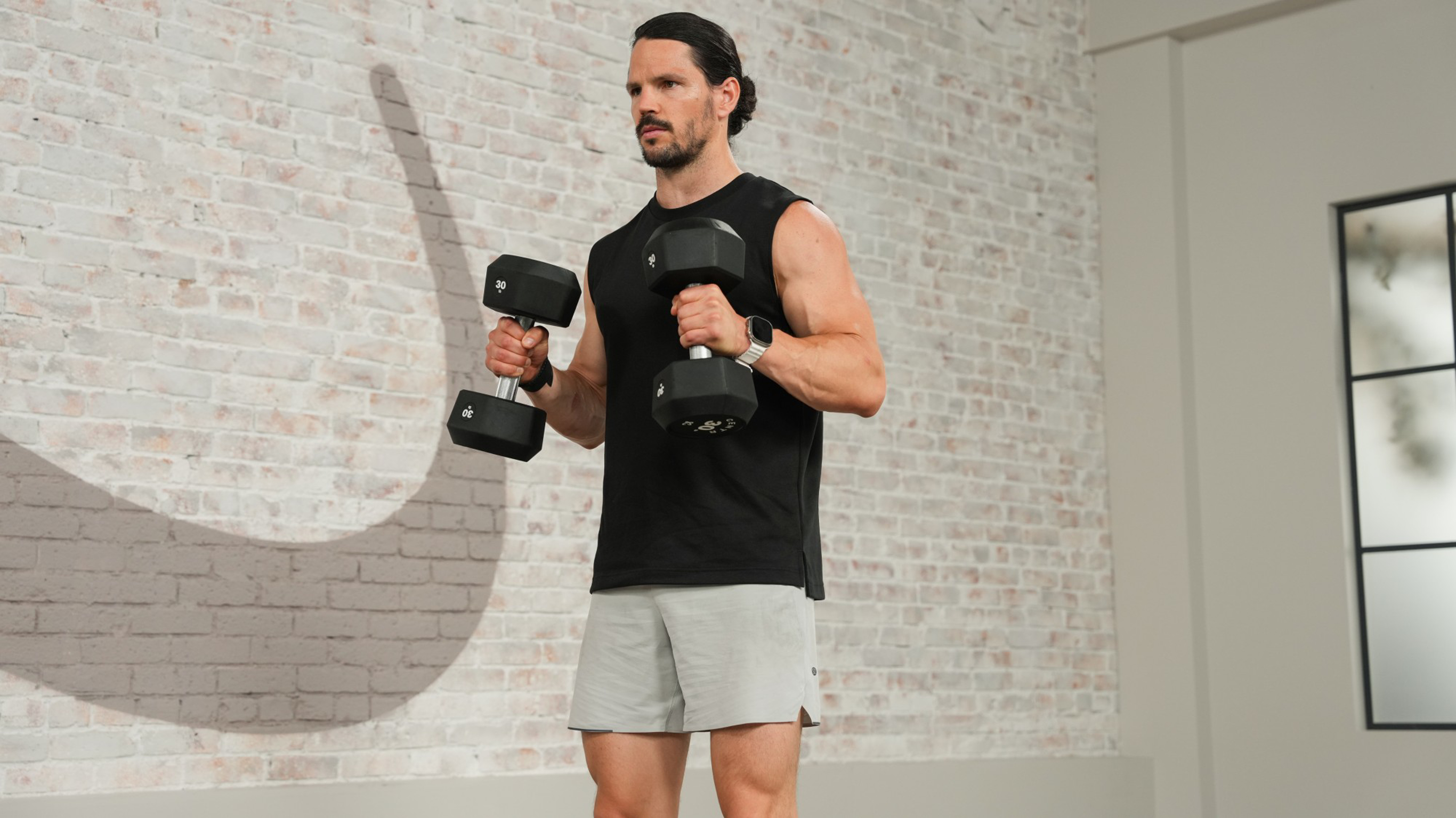 Centr trainer Dan Churchill performs dumbbell bicep curls in the Centr studio gym.