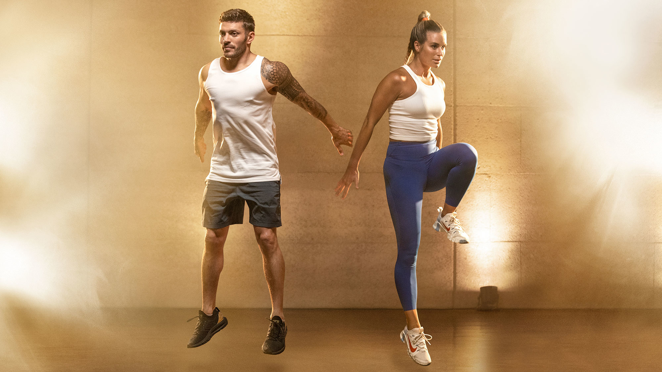 Centr trainers Luke Zocchi and Alexz Parvi jump explosively in the air, surrounded by golden lighting.