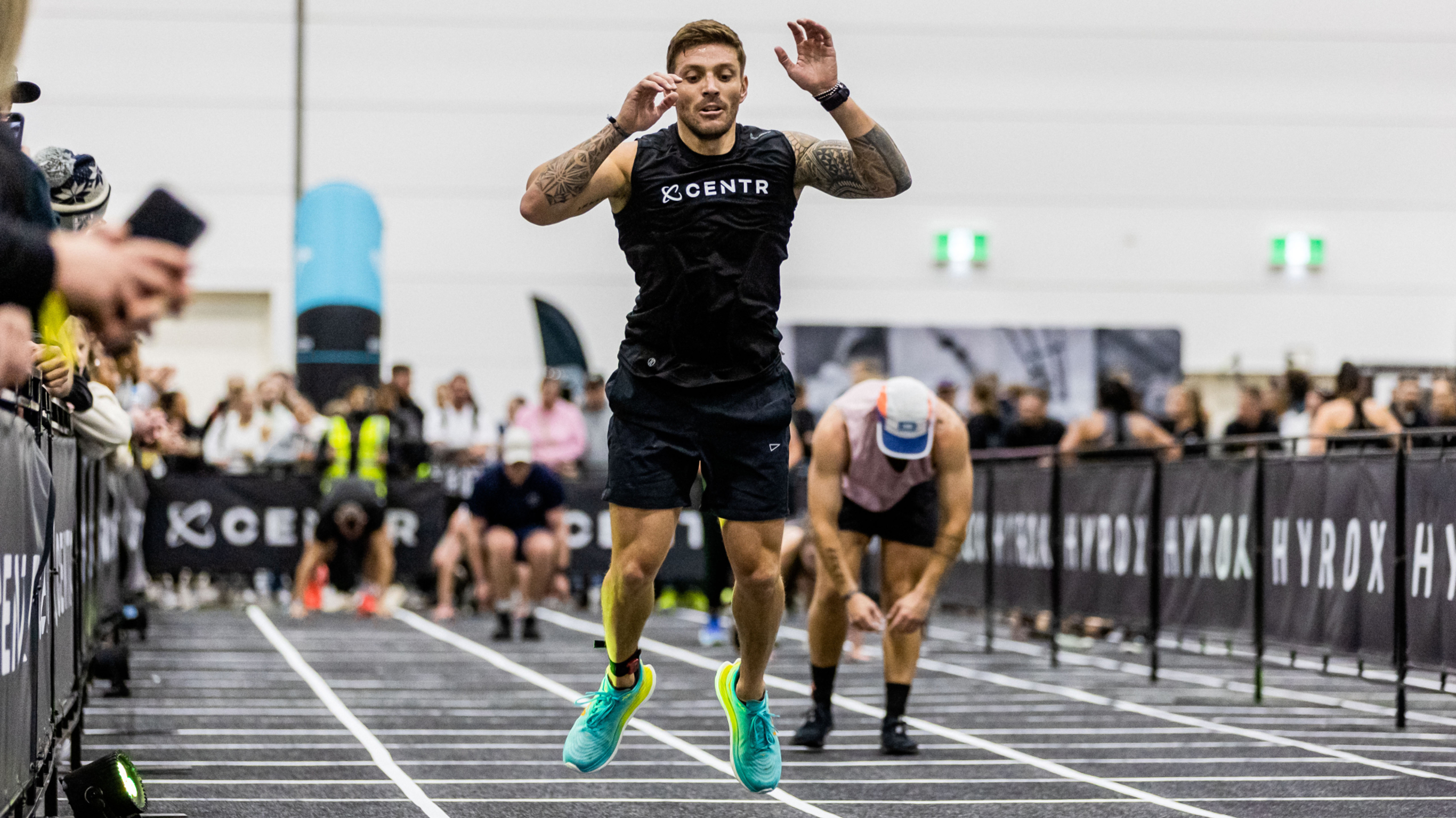 Centr trainer Luke Zocchi competes in the burpee broad jump section of a HYROX race