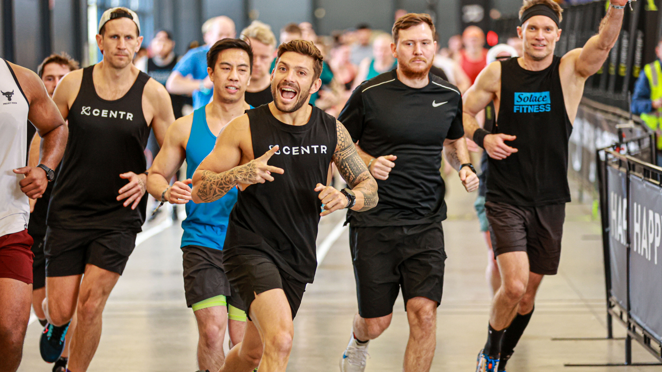 Luke Zocchi says hi to the photographer during a run leg at a HYROX competition.