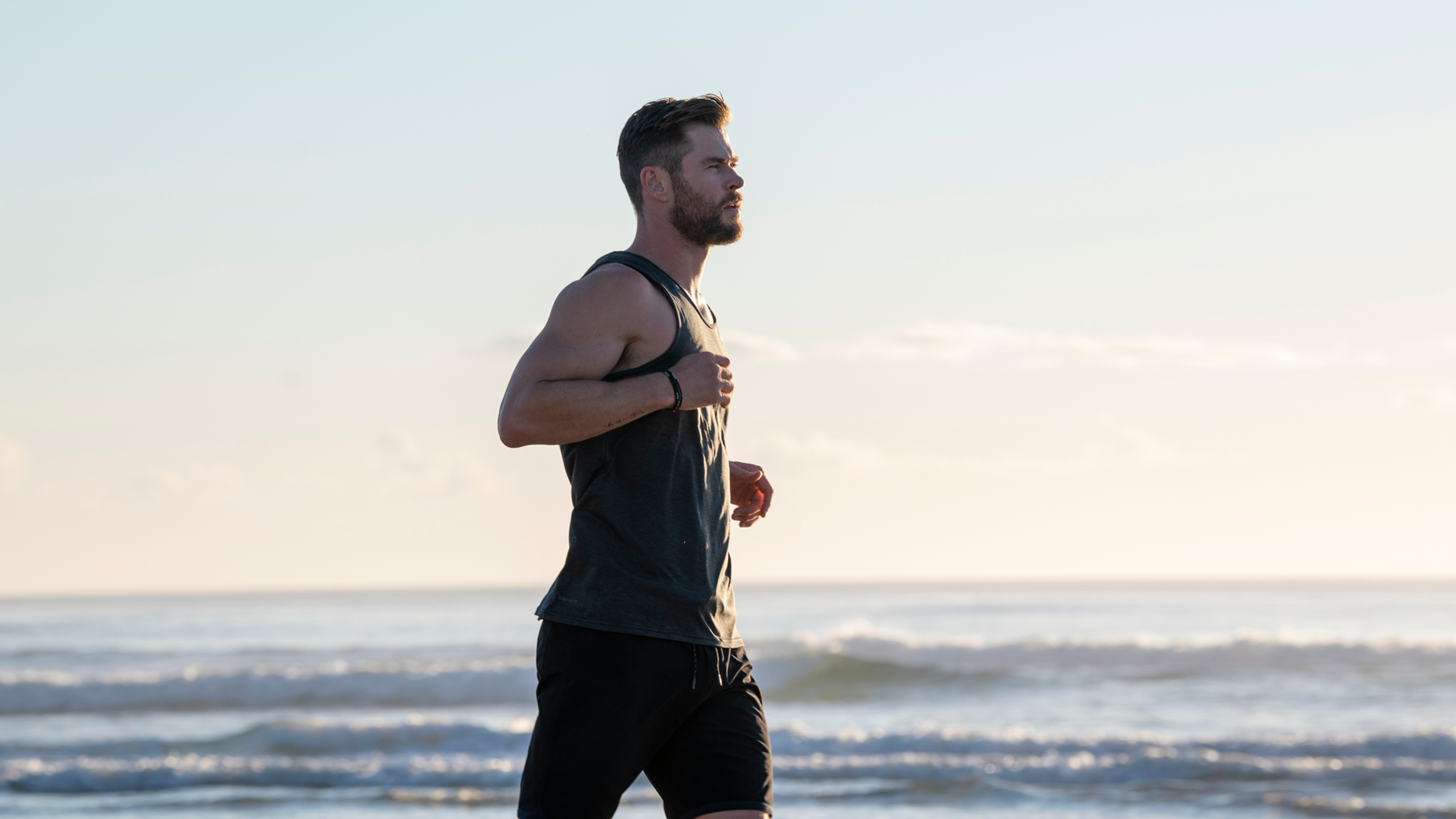 Chris Hemsworth jogs on the beach.