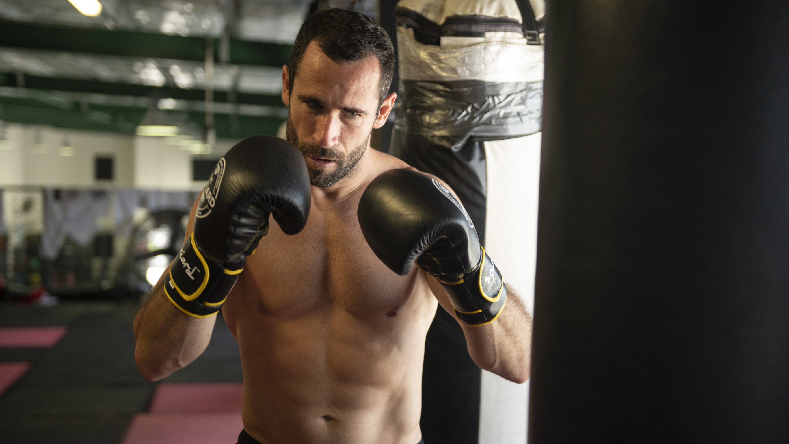 Jorge Blanco, wearing boxing gloves, aiming at a black punching bag.