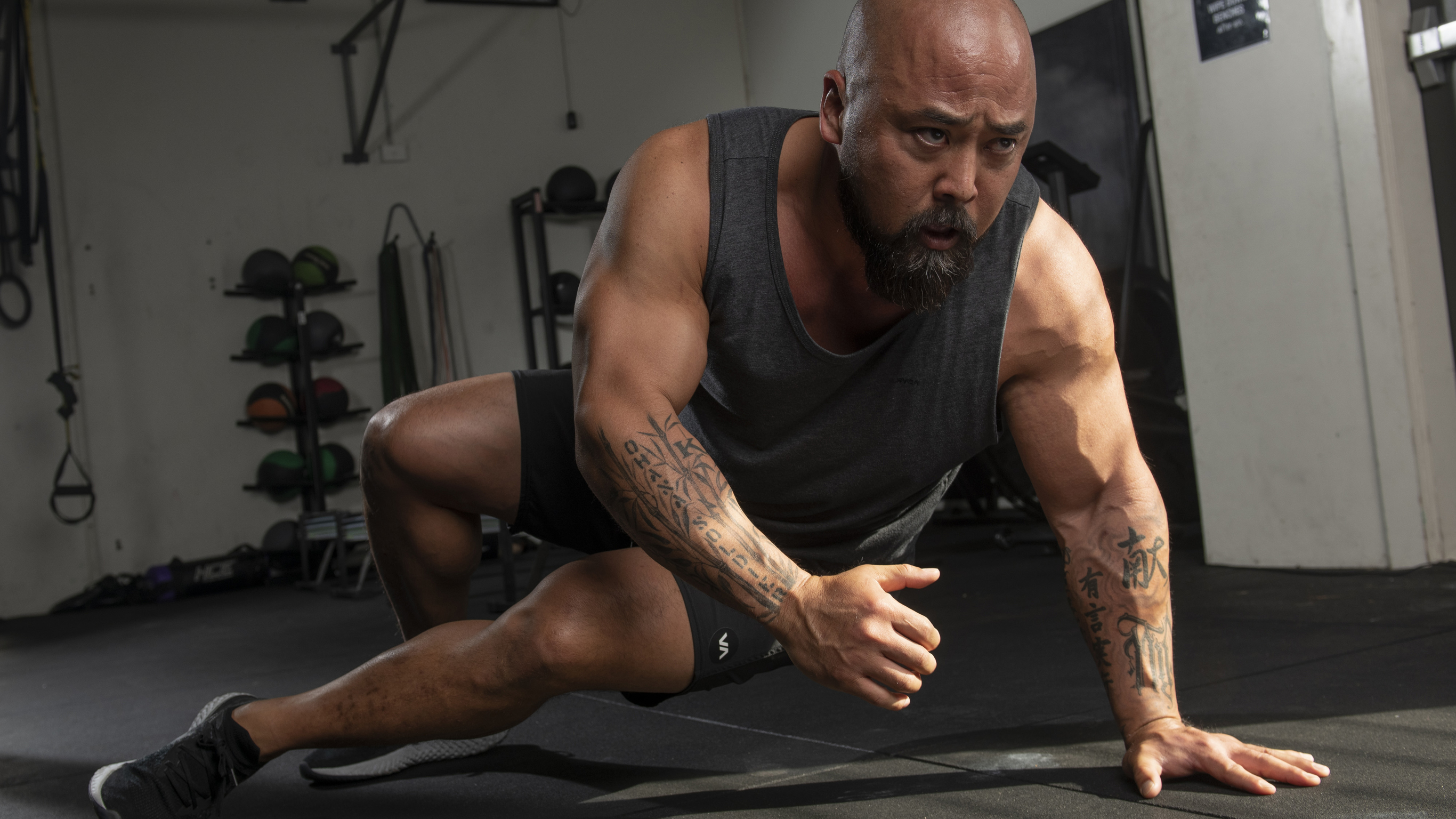 Joseph 'Da Rulk' Sakoda performing a sit thru exercise in a gym.