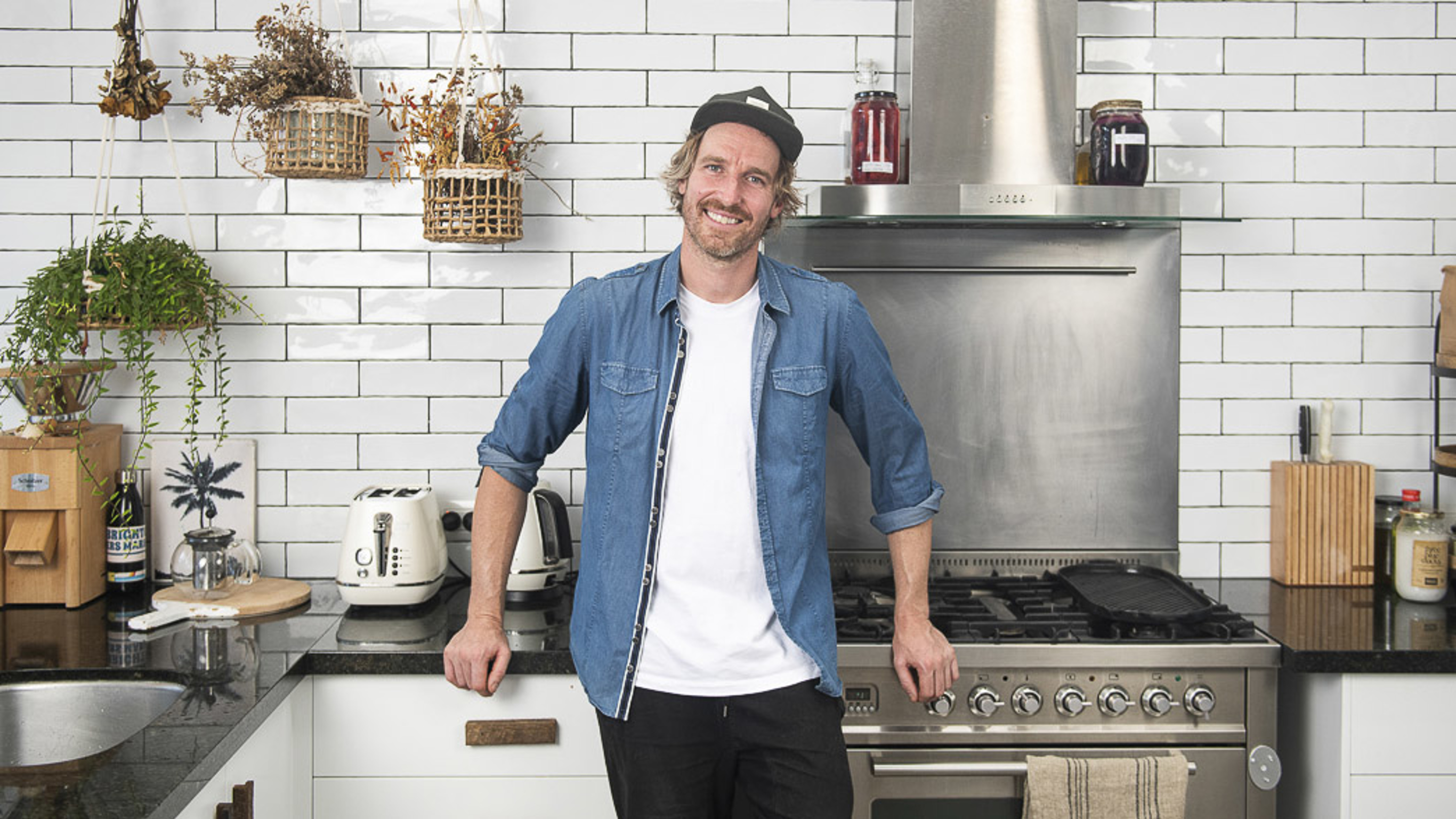 Darren Robertson leans against the counter in a modern kitchen.