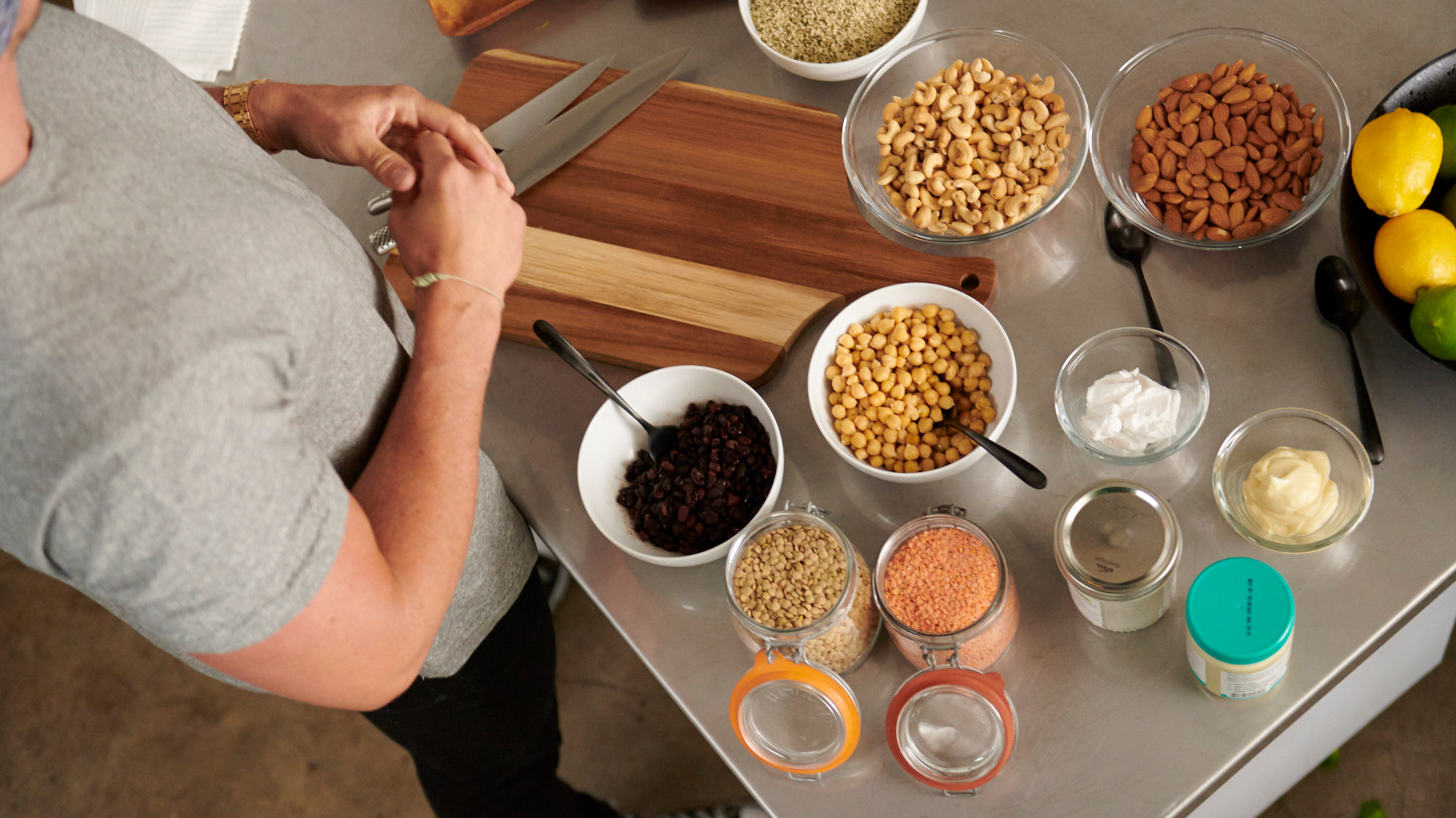 Chopping board surrounded by bowls of dried legumes like lentils and chickpeas.