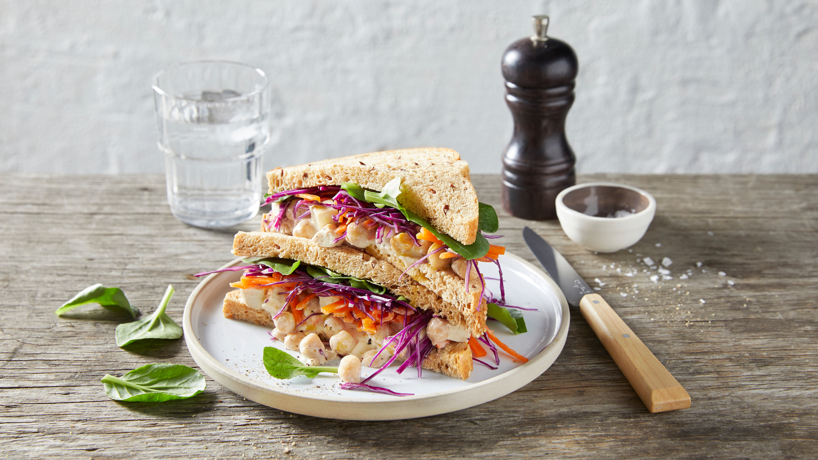 A pile of Centr's Plant-packed Protein Sandwiches sits on a plate on a wooden table.