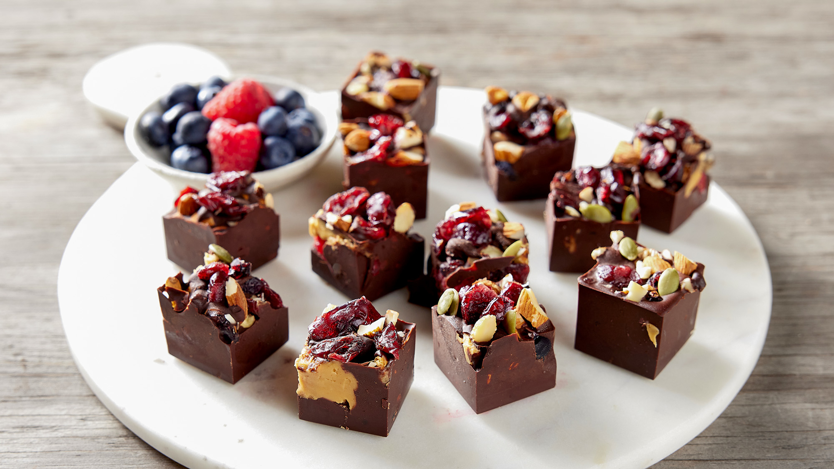 A round marble serving platter holds a dozen pieces of Berry, Choc & Nut Ice Cube Bites, ready for eating.