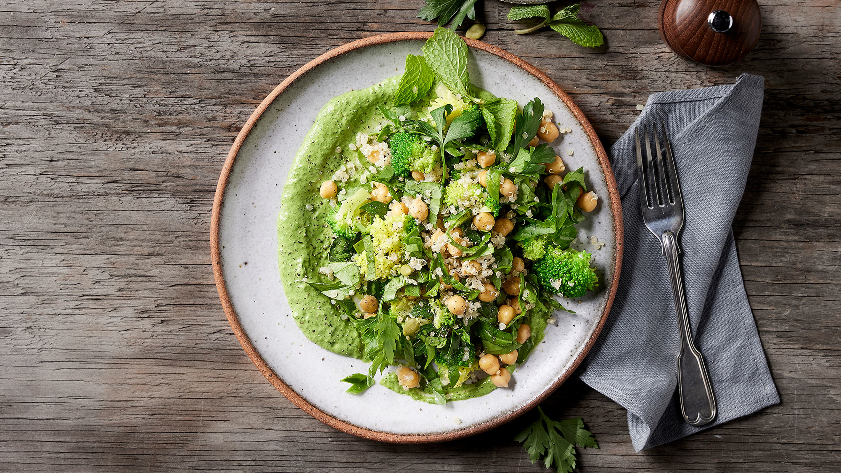 A plate of Centr's Fibre-packed Chickpea Salad with Green Tahini sits on a rustic table, ready for eating.