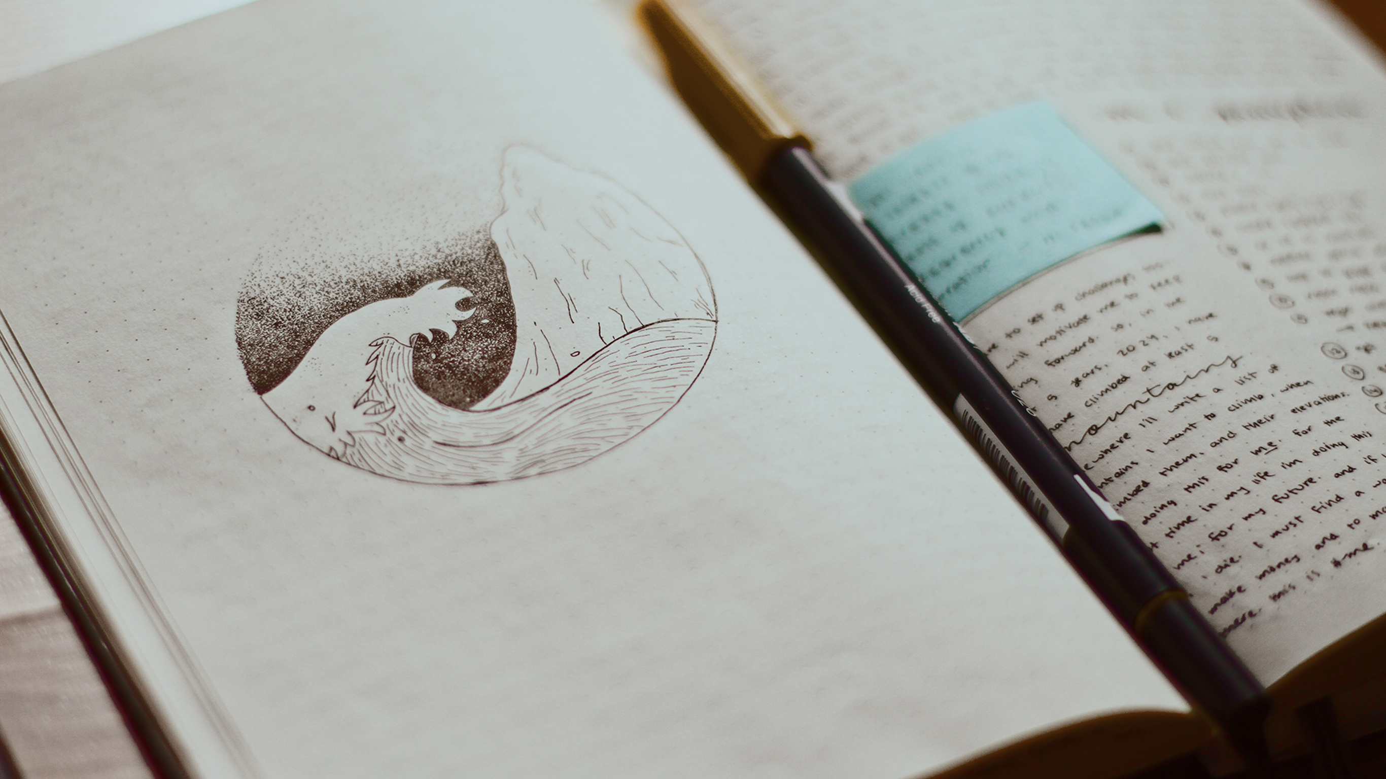 An open journal with the drawing of a wave on one page and notes on the other.