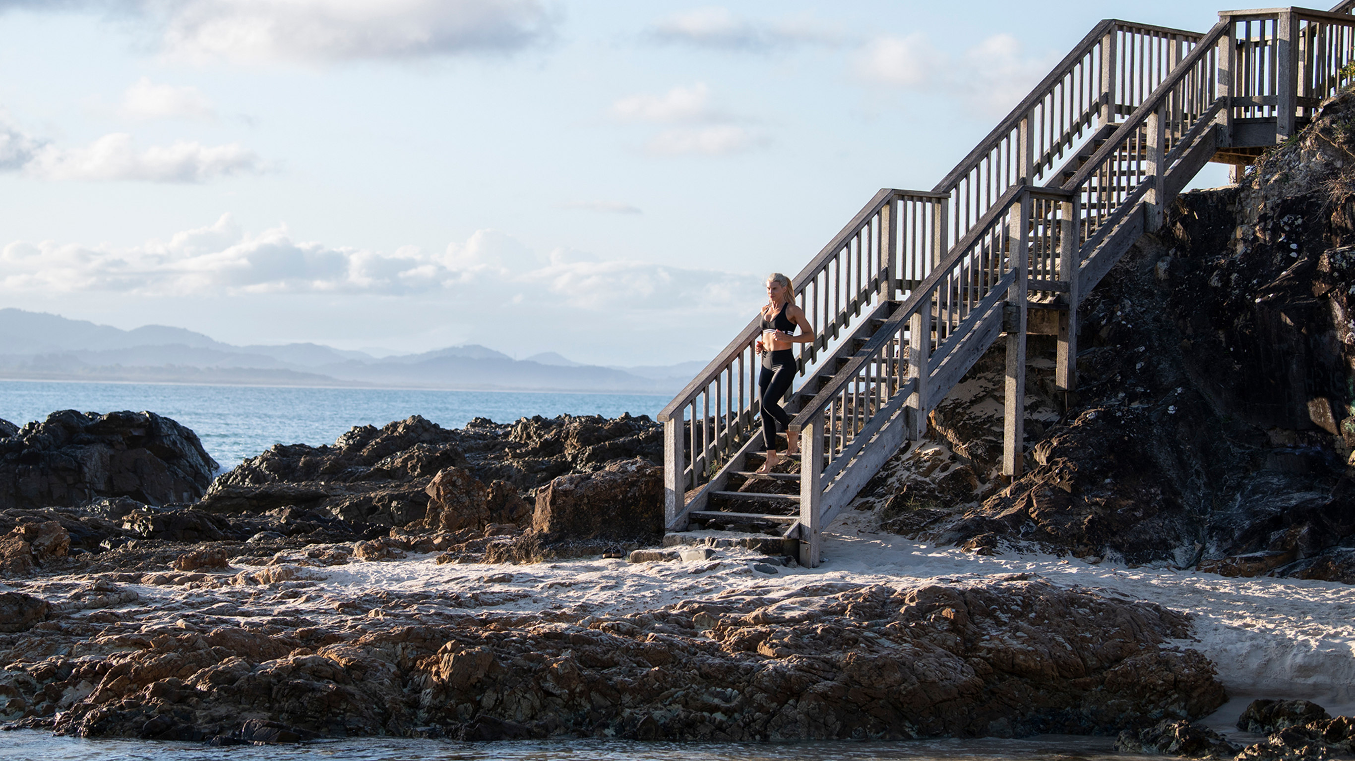 Tiffiny Hall runs down a wooden staircase to the beach.